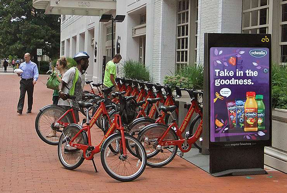 Bike share station domination with branded dock wraps near a busy plaza