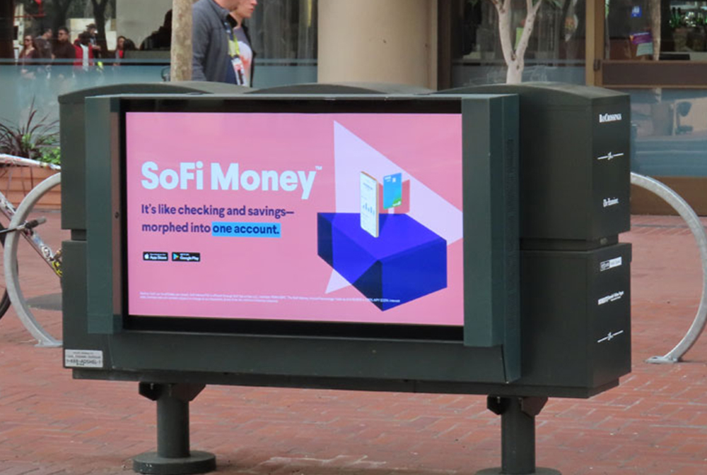 Urban panel advertising at pedestrian eye level along a busy retail corridor